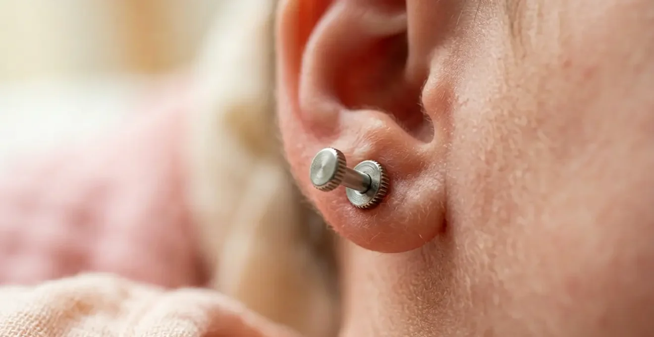 Detalle macro de cierre de rosca en pendiente infantil con mano de bebé borrosa al fondo