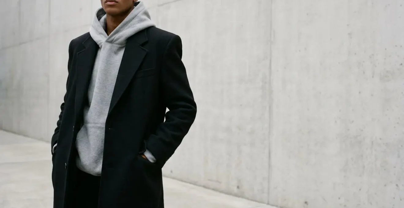 Combinación de sudadera con capucha gris bajo abrigo de lana negro con solapas estructuradas