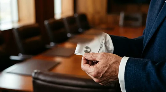 Ejecutivo profesional ajustándose discretos gemelos de plata en el puño francés de su camisa en un entorno de oficina